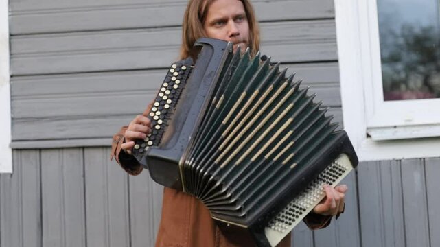 Male musician plays the accordion in the yard