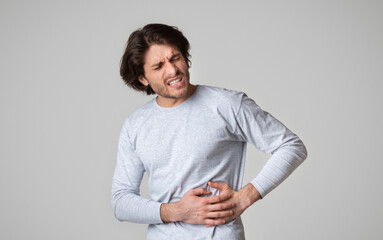 Liver pain. Guy holds hands on his side with torment facial expression