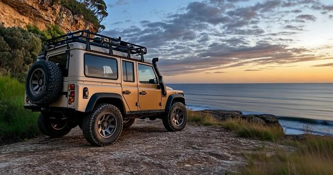Video of a generic off-road vehicle parked on a cliff edge overlooking the ocean at sunset with a rocky cliffside and a colorful sky