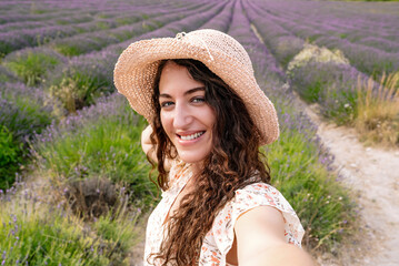 Happy woman taking selfie in blooming lavender field during summer