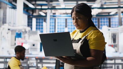 Woman engineer in photovoltaics factory uses tracking software on laptop to diagnose malfunctioning...