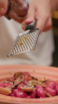 Hands Of The Waiter Grating Bottarga Over The Pink Dumplings Gourmet Dish 