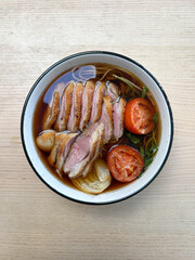 A bowl of noodle soup with duck breast.