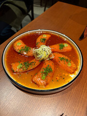 A plate of salmon sashimi in a broth sauce.
