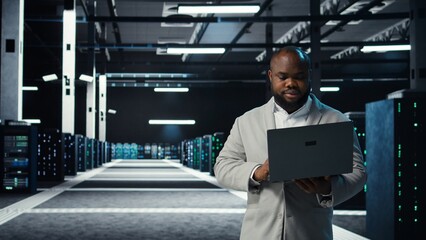 Data center engineer coding on laptop, doing software updates for mainframes. Server farm IT...