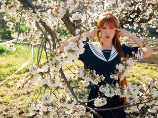 Cherry Trees Bloom While a Redhead Poses Playfully in a Traditional Outfit Under a Bright Sky