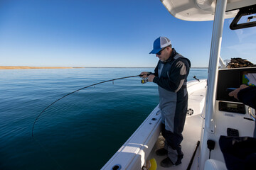 Fisherman on a boat reeling in his line.