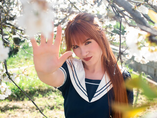 Redhead Woman in Sailor Outfit Enjoying Cherry Blossoms in Springtime Garden