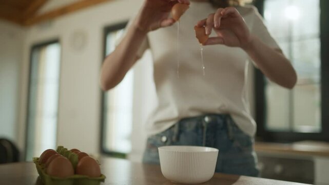 Woman cracking eggs into bowl in slow motion