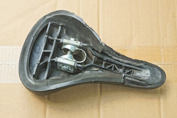 one old black leather bicycle saddle lies on a brown cardboard table