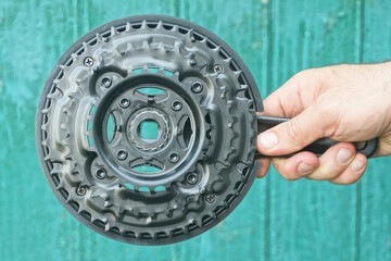 hand holds one detail of a sports bicycle made of black iron bicycle sprockets with a knee for a...