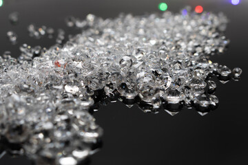Sparkling loose diamonds scattered on a glossy black surface with colorful bokeh lights in the background, highlighting brilliance, luxury, and elegance in a modern, high-contrast composition.
