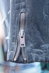 one black leather sleeve of an old jacket with a gray metal zip on a spring street