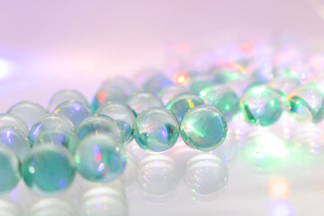 Close-up of transparent glass marbles with colorful reflections on a reflective surface –...