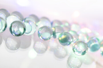 Iridescent Glass Marbles in Green, Blue, and Purple on Reflective Surface with Light Refractions