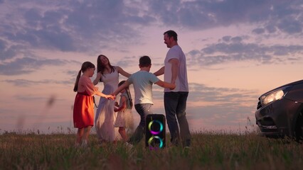 Children, parents dance in nature, holiday, sunset. Family travels by car. People dance in light of car headlights, camping. Happy family child dance weekend by car. Parents child have fun with music