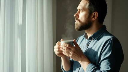 Bearded man enjoys morning coffee by window
