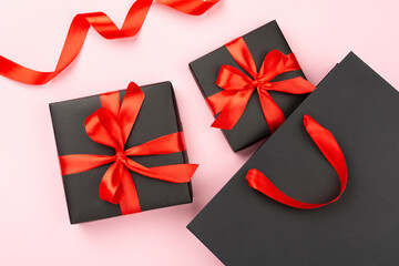 Black shopping bag and gift boxes on color background, top view.Black Friday concept