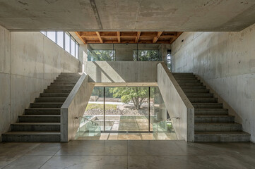 Modern concrete interior featuring staircase and natural light