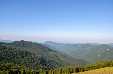 Breathtaking landscape depicting rolling green hills covered in dense forests against the backdrop...