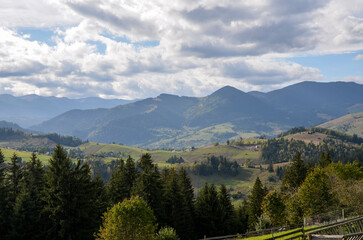 Breathtaking view of mountain valley featuring lush green slopes, distant peaks, and vast evergreen...