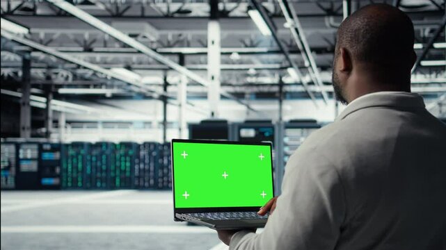 Data center admin using isolated screen laptop to monitor neural network AI. Server room employee using mockup notebook to oversee rigs powering machine learning processes, camera A