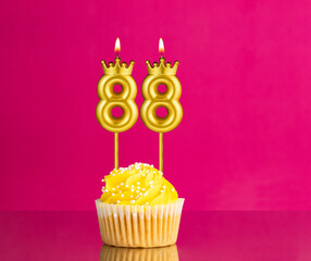Yellow birthday cupcake with a number 88 candle - Birthday card on a pink background