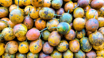 A pile of ripe passion fruits with colorful yellow, orange, and purple skins, freshly harvested and...