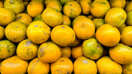A pile of ripe yellow-green oranges displayed in bulk, showing natural texture and fresh citrus appeal.
