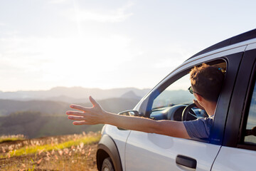 Traveler extends his arm out the car window, enjoying the view and freedom of the open road. A calm...