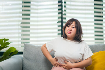 Asian teenage girl experiencing abdominal pain, possibly from menstrual cramps or a...