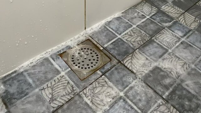 Water and foam flow to floor drain cover in bathroom