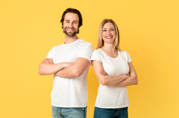 Smiling confident millennial caucasian guy and lady in white t-shirts with crossed arms on chest...