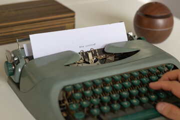 Hands typing on a vintage typewriter, conveying a message of optimism and mental wellness, with a...