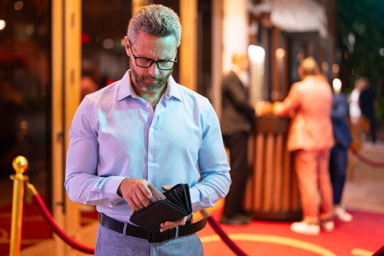 Rich business man holding wallet with money. Rich businessman counting dollars bills money. Wealthy rich man with a wallet and money cash. Businessman in urban nightlife hold wallet. Rich lifestyle.