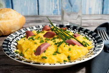 Delicious polenta with sausage and chives on rustic wooden table
