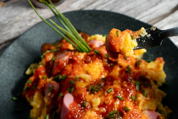 Fork lifting delicious bite of creamy polenta with sausage and tomato sauce