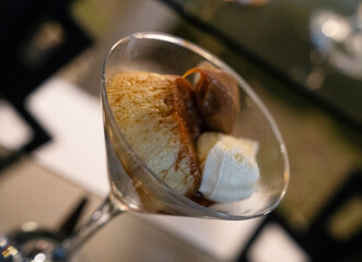 Traditional dessert in a social event. Closeup view of a delicious flan with dulce de leche and cream, presented in a cup of glass