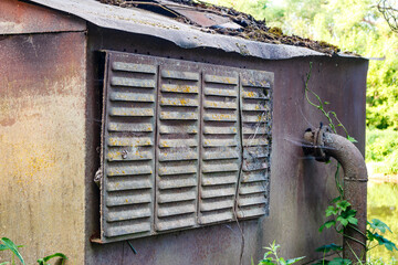 Old rusty and abandoned utility room for a pumping station in the countryside
