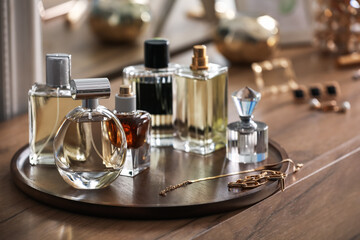Bottles of different perfumes and accessories on wooden table, closeup
