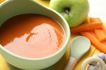 Baby food. Tasty puree in bowl, different ingredients and teether on table, closeup