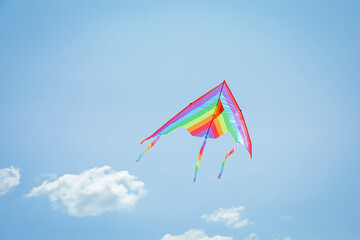 Colorful kite flying in blue sky, low angle view