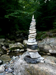 Stack of flat stones balanced by the river shore. Peaceful natural setting. Vertical photo