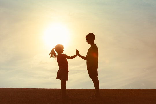 Brother and sister as happy siblings giving high five, family togetherness, childhood concept 
