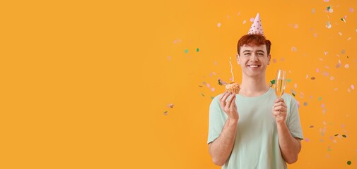 Young man with birthday cake and glass of champagne on yellow background with space for text
