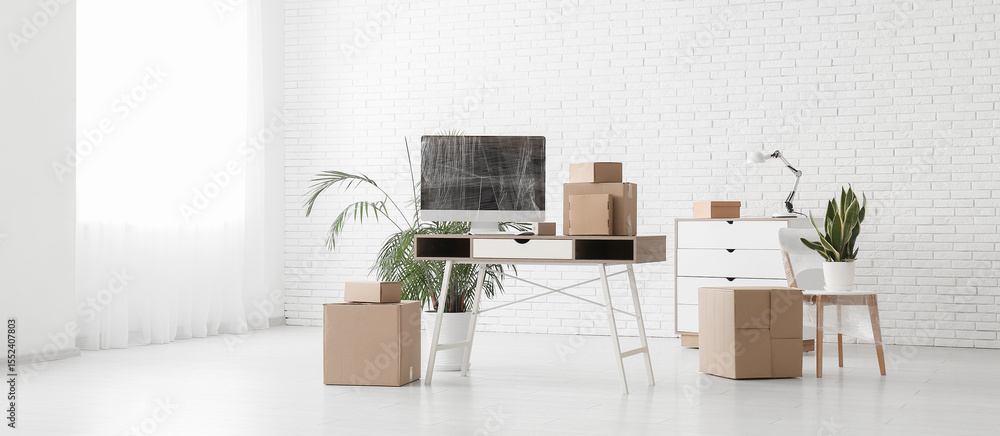 Poster workplace with wrapped computer monitor and cardboard boxes in office on moving day