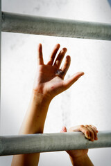 Hands Reaching for Freedom Through Metal Bars in Soft Light