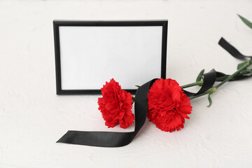 Blank funeral frame, carnation flowers and blank ribbon on light background