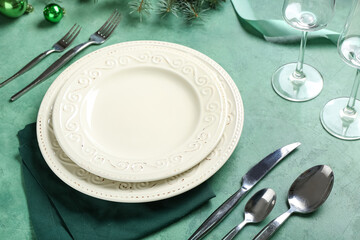 Beautiful table setting with Christmas balls on green background