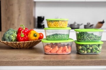 Fresh and frozen vegetables on wooden table in kitchen